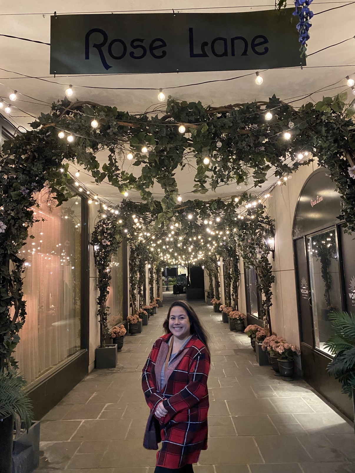 Fatima beneath a flower-covered archway with string lights